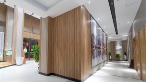 Corredor moderno de hotel com painéis de madeira, parede de vidro e piso ladrilhado.