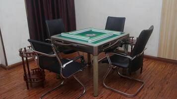 Une pièce avec une table à carreaux verts et blancs, quatre chaises noires et un plancher en bois.