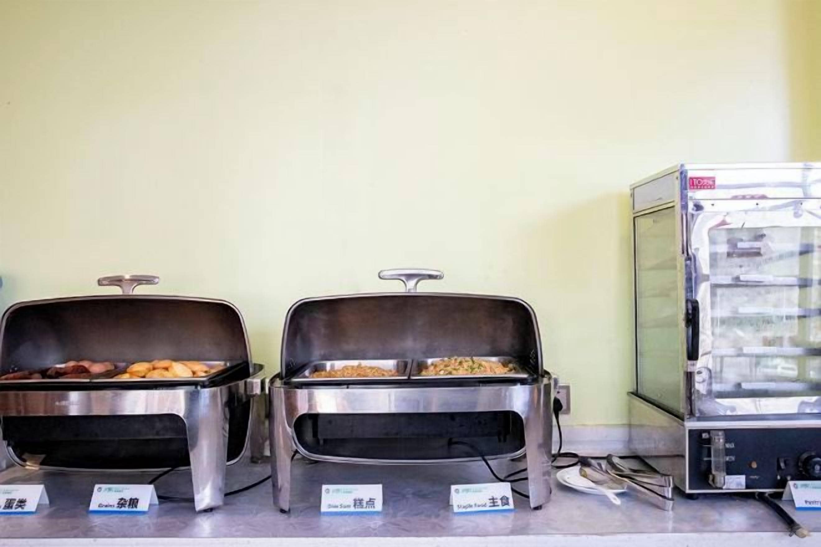 Dos estaciones de buffet con recipientes de comida y un microondas.