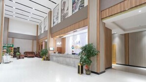 Um hall amplo com balcão de recepção, área de estar e plantas em vasos.