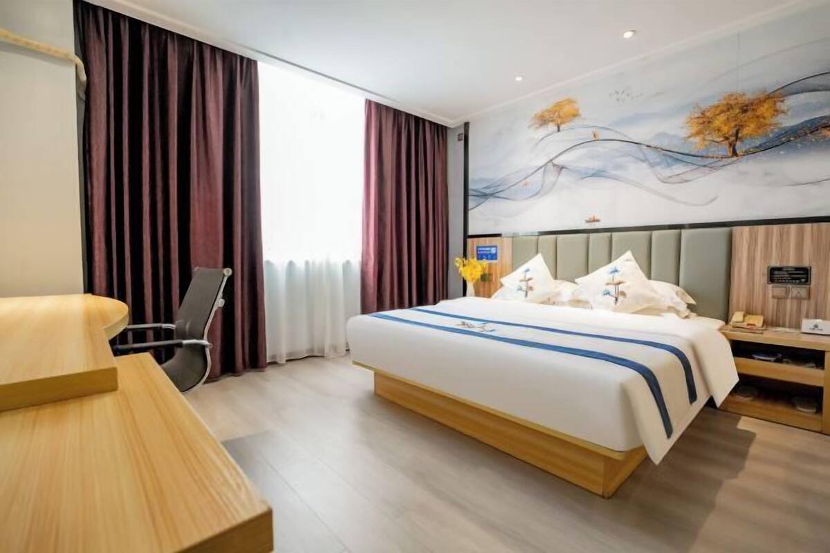 Une chambre d’hôtel avec un grand lit, un bureau, une chaise et un tableau au mur.