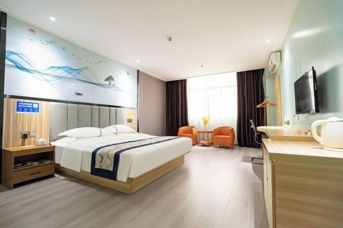 Une chambre d’hôtel équipée d’un lit, d’un bureau, d’une chaise, d’une télévision et d’un mur orné d’une fresque.