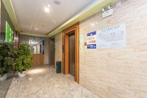 Um saguão de hotel com um balcão de recepção, uma porta de madeira e uma placa com um mapa.