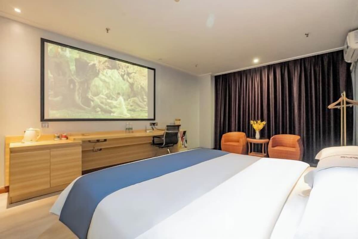 Une chambre d’hôtel équipée d’un lit, d’un bureau, d’une chaise, d’un écran de télévision et d’une fenêtre avec des rideaux.