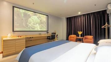Habitación de hotel con cama, escritorio, silla, televisor y ventana con cortinas.