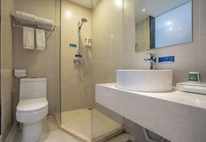 Une salle de bain moderne avec une douche à parois de verre, des toilettes blanches et un grand lavabo surmonté d’un miroir.