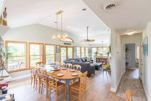 A spacious living area with a dining table, chairs, a sofa, and a ceiling fan.