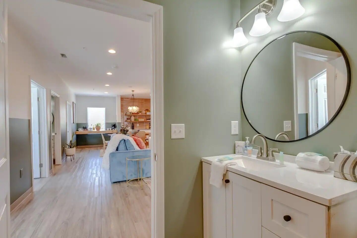 A modern bathroom with a round mirror, white sink, and a towel rack.