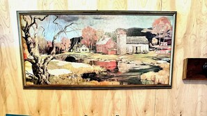 Une cuisine dotée d’un plan de travail en granit, d’un évier à deux bacs, de meubles en bois et d’un tableau accroché au-dessus de l’évier.