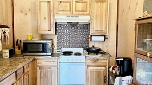 Une cuisine avec des meubles de rangement en bois, une cuisinière, un four à micro-ondes et une machine à café.