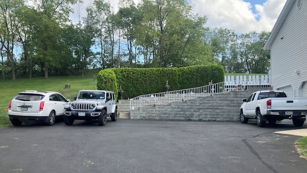 A parking area with three white vehicles parked in front of a building with a stone staircase and a hedge. - Charming 3-bed countryside house in Northampton with WiFi and AC (Northampton)