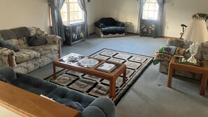 A living room with a sofa, armchair, coffee table, and a side table with a lamp. - Charming 3-bed countryside house in Northampton with WiFi and AC (Northampton)