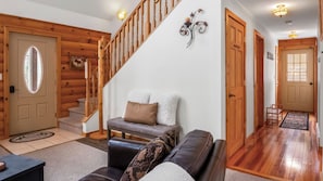 A wooden interior with a staircase, a sofa, and a door with a window.