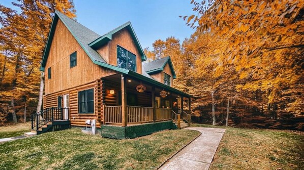 A log cabin with a porch, a staircase, and a pathway leading to the entrance.