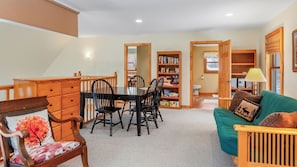 A cozy living room with a dining table, chairs, a sofa, and a bookshelf.