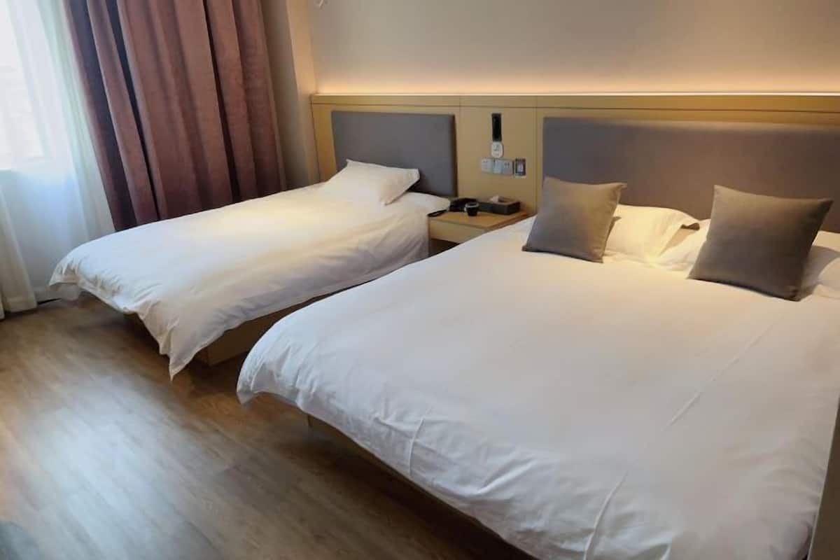 Une chambre d’hôtel avec deux lits, un plancher en bois et une table de chevet équipée d’un téléphone et d’une lampe.