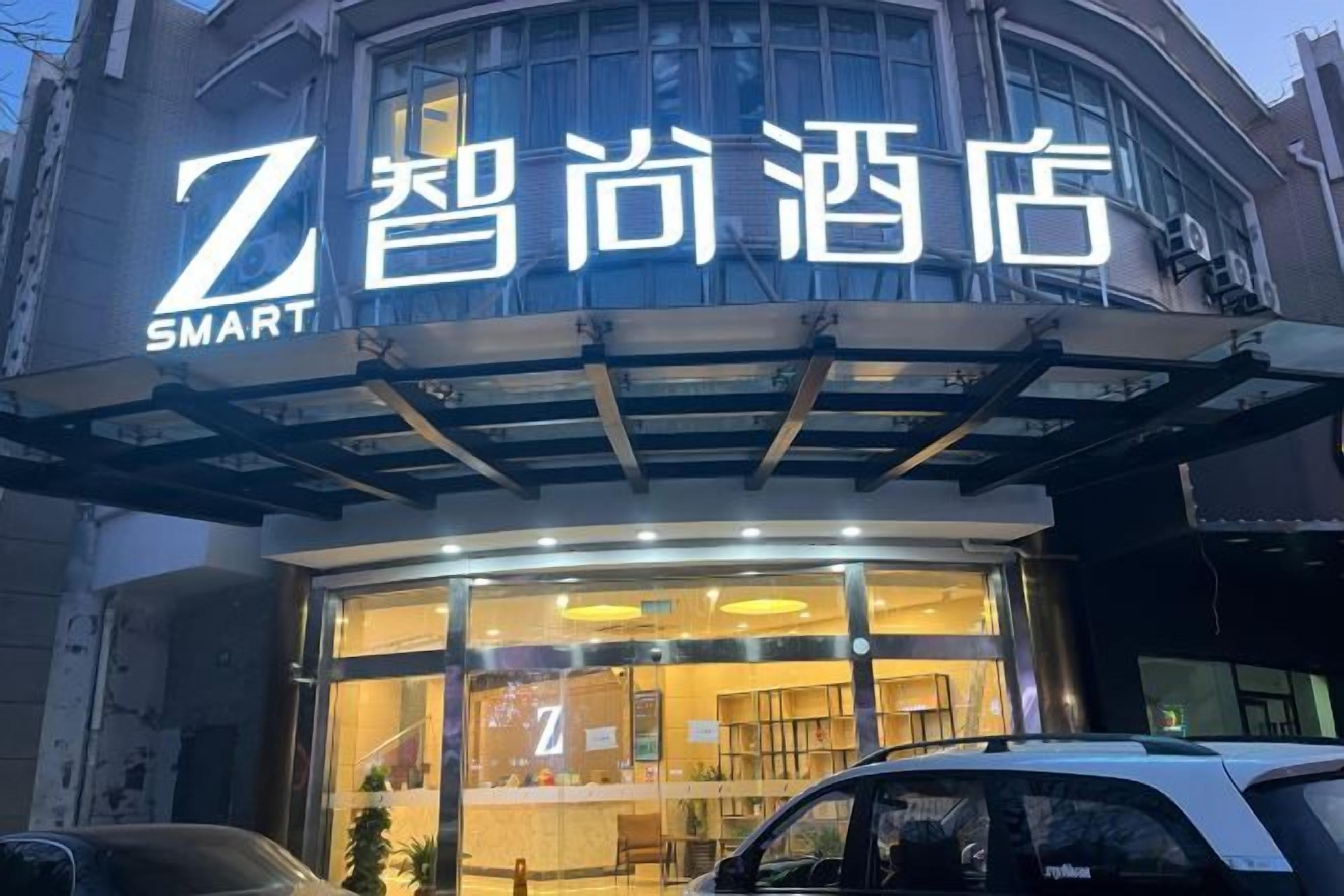 L’entrée d’un hôtel, avec une enseigne bien visible indiquant « Z SMART », de grandes fenêtres en verre et un espace d’entrée abrité.