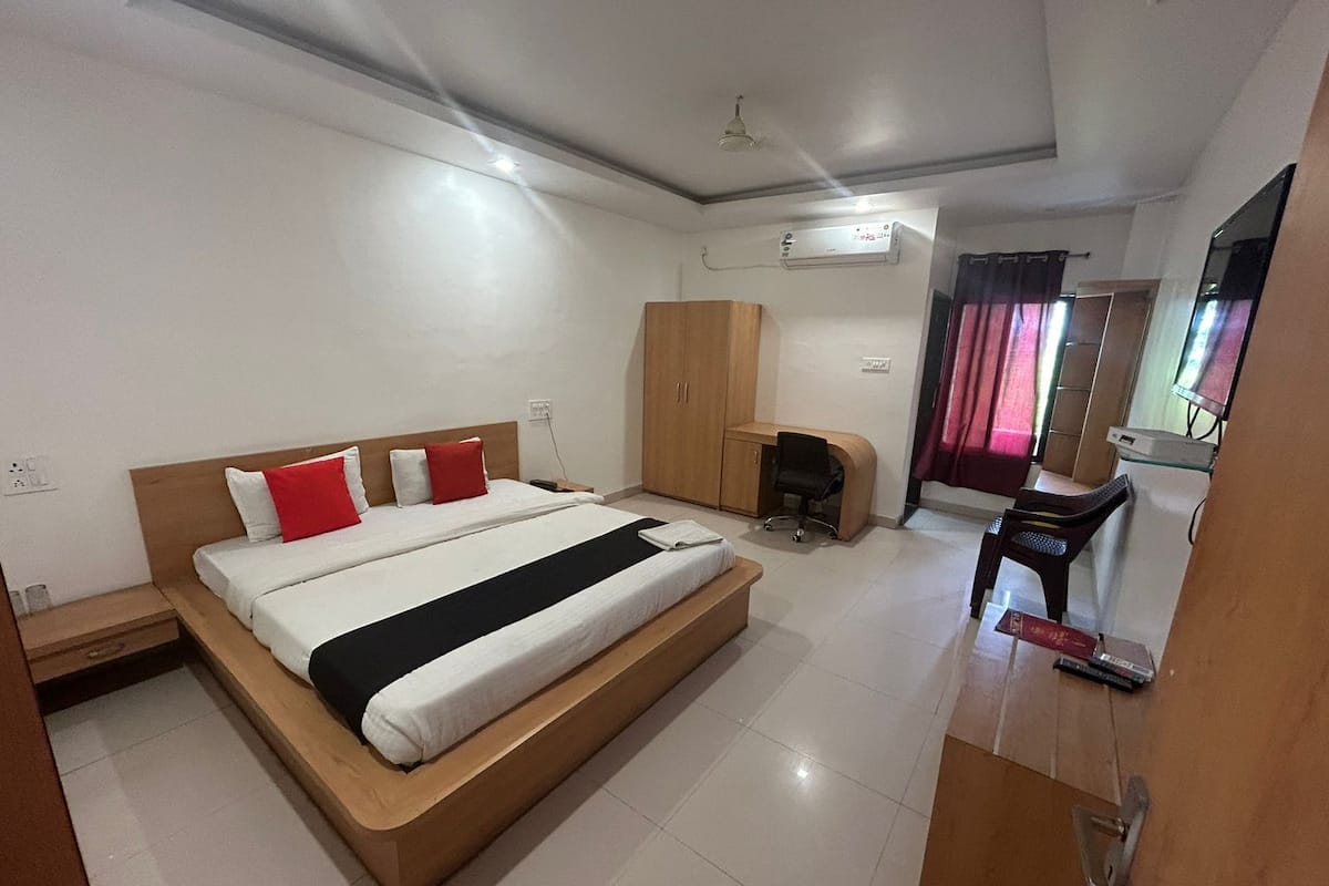 A hotel room with a large bed, a desk, a wardrobe, and a ceiling fan.