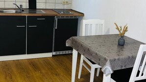 A kitchen with black cabinets, a white countertop, and a dining table with white chairs. - Family and Friends Dannstadt (Dannstadt-Schauernheim)