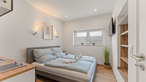 A modern bedroom with a bed, bedside table, and a window. - Family and Friends Dannstadt (Dannstadt-Schauernheim)