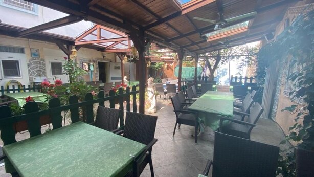 An outdoor patio area with tables and chairs, covered by a wooden roof, and surrounded by a decorative fence. - Family and Friends Dannstadt (Dannstadt-Schauernheim)