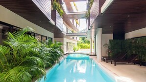 Een binnenzwembad met een modern ontwerp, omringd door weelderige begroeiing en houten details.