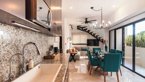Een moderne keuken met granieten aanrechtbladen, een witte spoelbak en roestvrijstalen apparatuur.