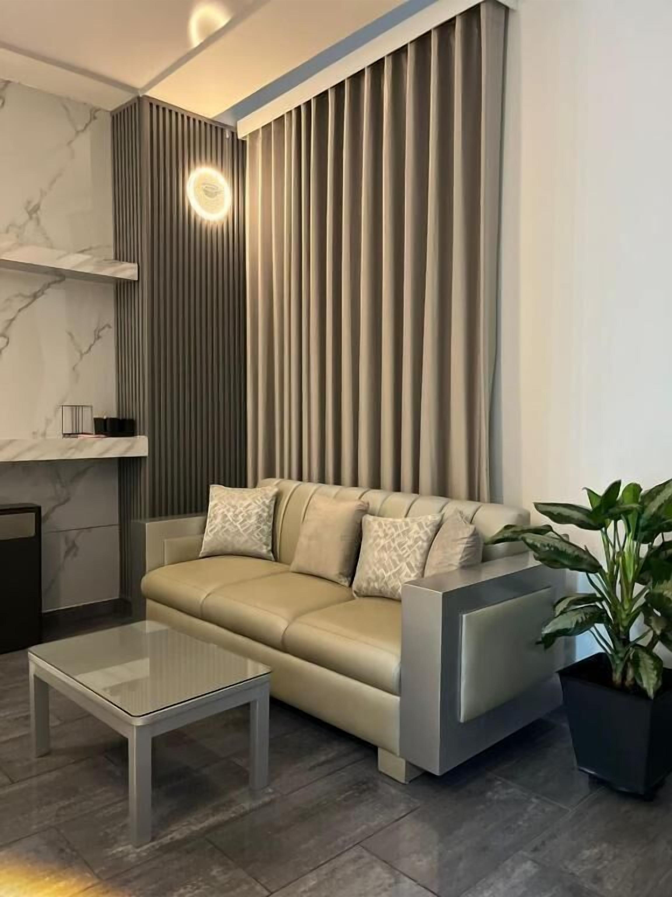 A modern living room with a sofa, a glass coffee table, and a potted plant.