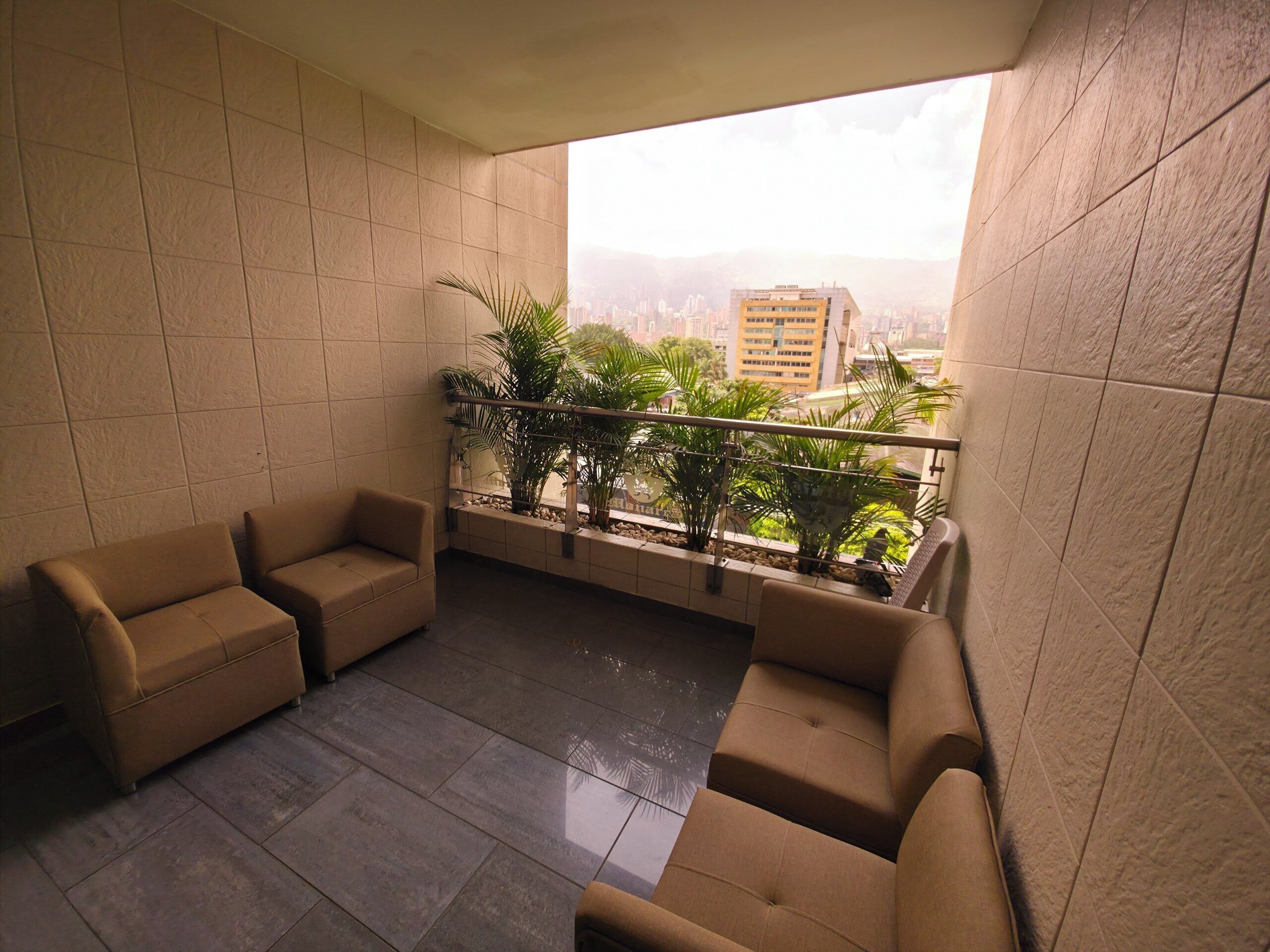 Ein Balkon mit Sitzgelegenheit, Blumentöpfen und Blick auf die Stadt.
