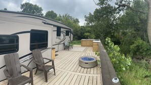 Ein Wohnmobil mit einer Terrasse, zwei Stühlen, einer Feuerstelle und einer Holzbank.