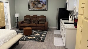 A compact room with a bed, a sofa, a dining area, and a kitchenette.