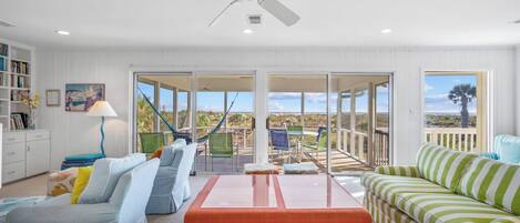 A spacious living room with a large window, a ceiling fan, and a view of the outdoors.