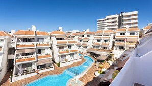 Un resort con varias edificaciones blancas, una piscina central y un cielo azul despejado.