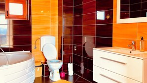 A modern bathroom with a bathtub, toilet, and vanity.