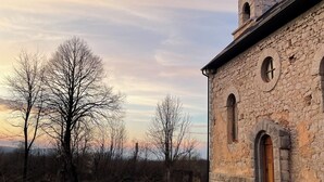 A stone church with a bell tower and arched windows.
