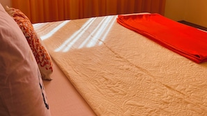 A bedroom with a bed, a pillow, a blanket, and a window with curtains.