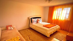 A hotel room with a bed, a sofa, and a small table.