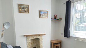 A living room with a fireplace, a sofa, a small table, and a window with curtains. - 4-6 Guests in centre location with stunning views (Llanberis)