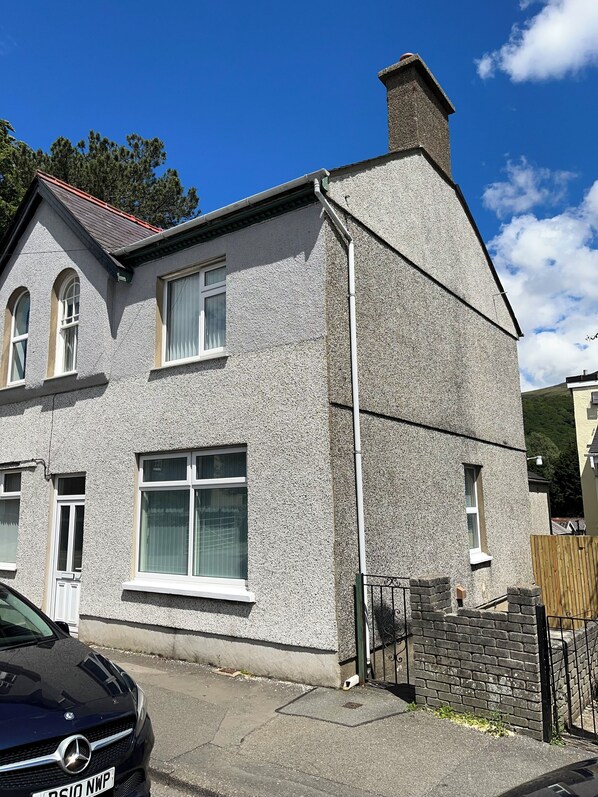A two-story house with a grey textured exterior, a red roof, and a chimney. - 4-6 Guests in centre location with stunning views (Llanberis)