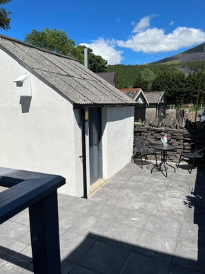 A courtyard with a white building, a wooden table, and outdoor seating. - 4-6 Guests in centre location with stunning views (Llanberis)