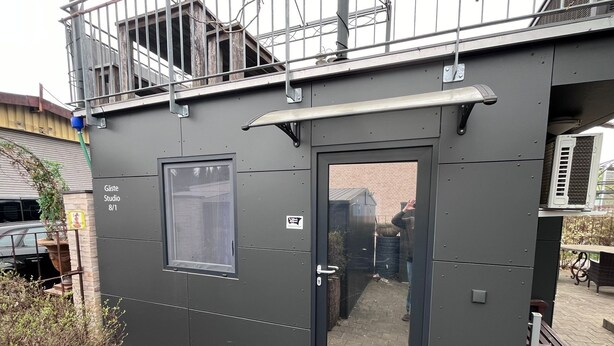 A modern building with a large window and a door, labeled "Gaste Studio 8/1". - Tiny House "Black Pearl" (Tettnang)