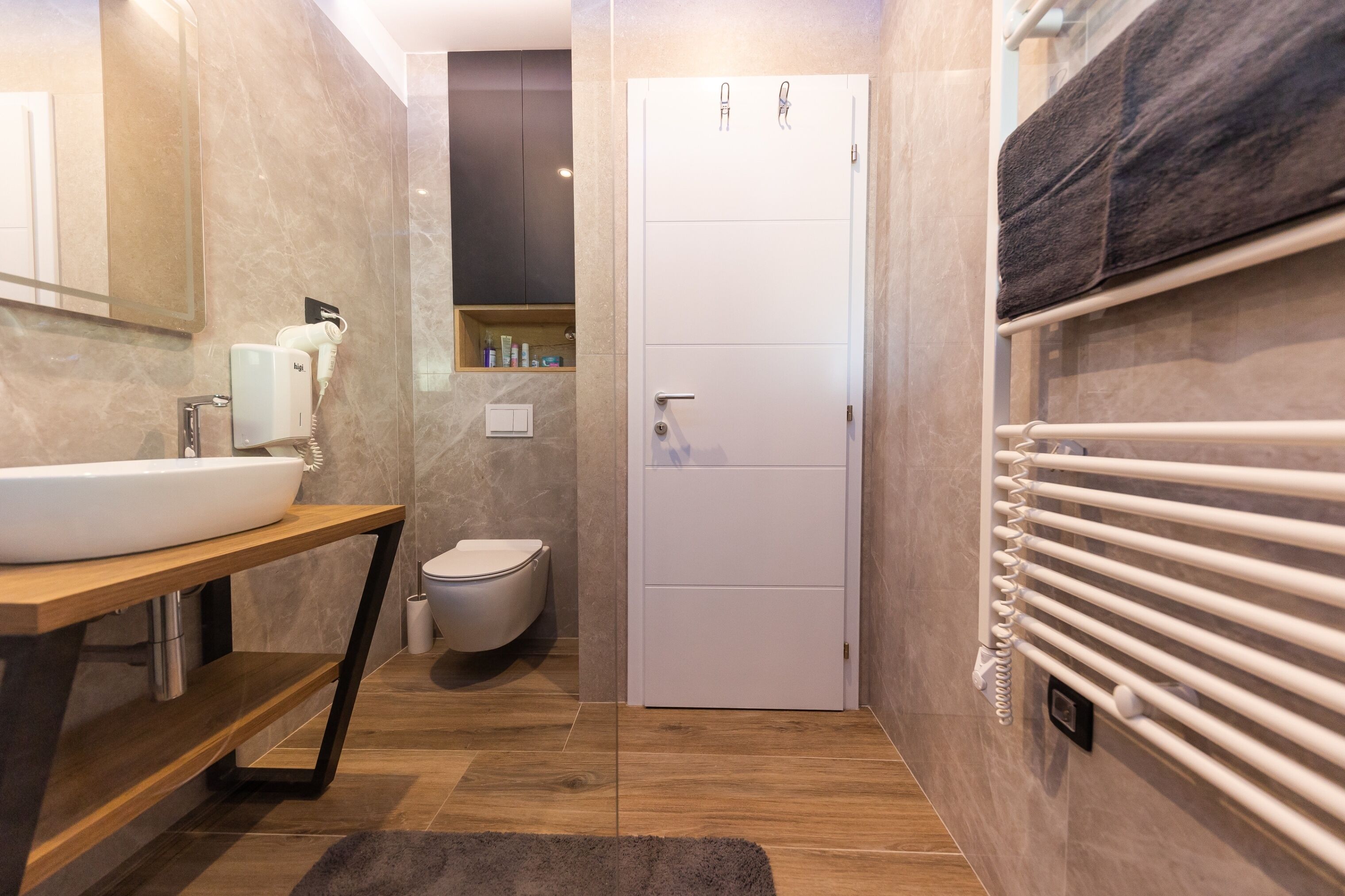 Een moderne badkamer met een wit wastafelmeubel, toilet en douche.