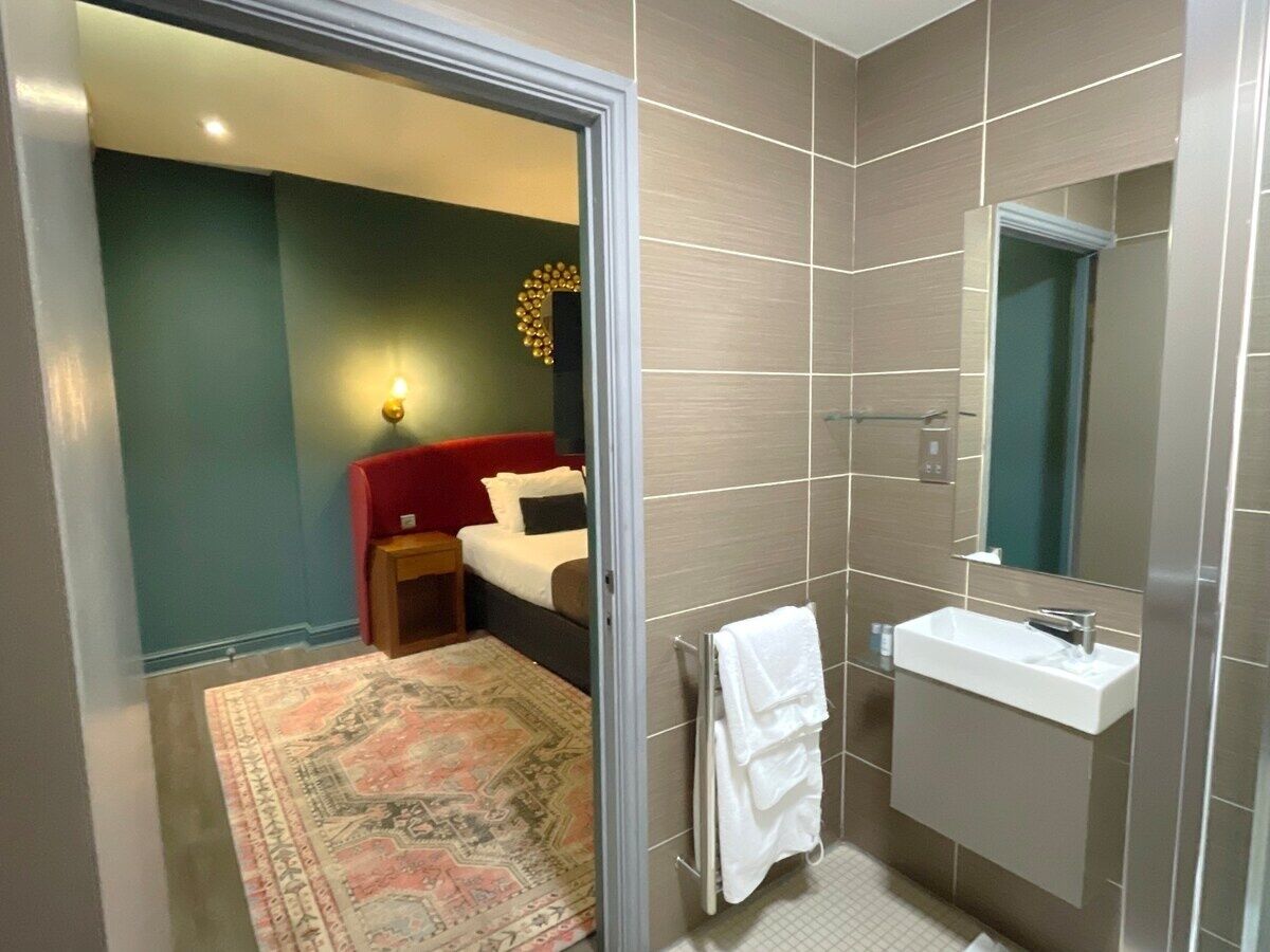 A hotel bathroom with a shower, a sink, and a mirror.