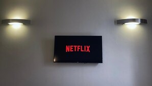 Un televisor montado en la pared con el logotipo de Netflix, flanqueado por dos apliques.