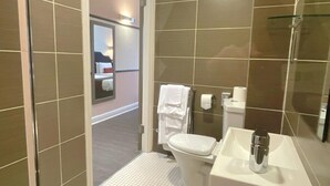 A modern bathroom with a white toilet, a sink, and a glass shower enclosure. - HNFC Stays - Business En-Suit (Tyne and Wear)