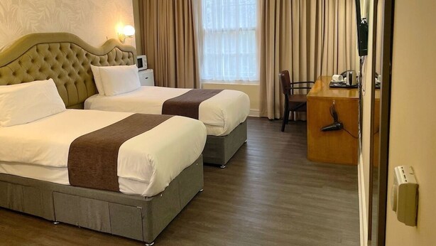 A hotel room with two beds, a desk, and a chair.