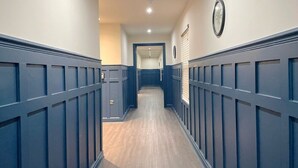 A hallway with blue wainscoting and a wooden floor.