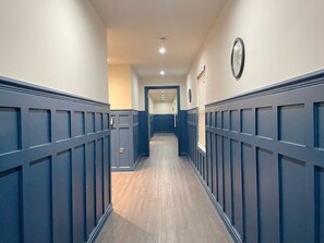 Stunning hallway with a symmetrical design, featuring a central walkway and paneled walls.
