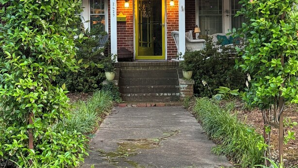 A house with a front porch, a green door, and a brick facade.