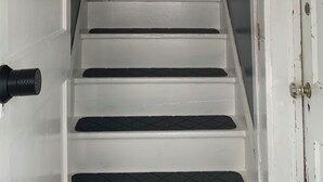 A staircase with white steps leading to a room with a door on the right.